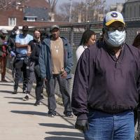Milwaukee voters wait in line to cast ballots, while social distancing, at Washington High School, April 7, 2020.