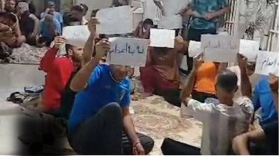 Prisoners occupy corridor at Ghezel Hesar Prison, holding signs that read “Sentenced to Death” and “No to Executions.”