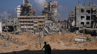 Palestinians walk through the destruction caused by the Israeli air and ground offensive in Gaza City, October 24, 2025.
