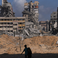 Palestinians walk through the destruction caused by the Israeli air and ground offensive in Gaza City, October 24, 2025.